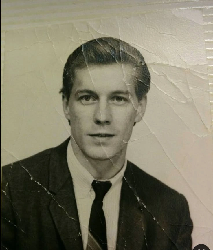 금이 간 인화지의 흑백 정장 차림 젊은 남성 인물 사진.